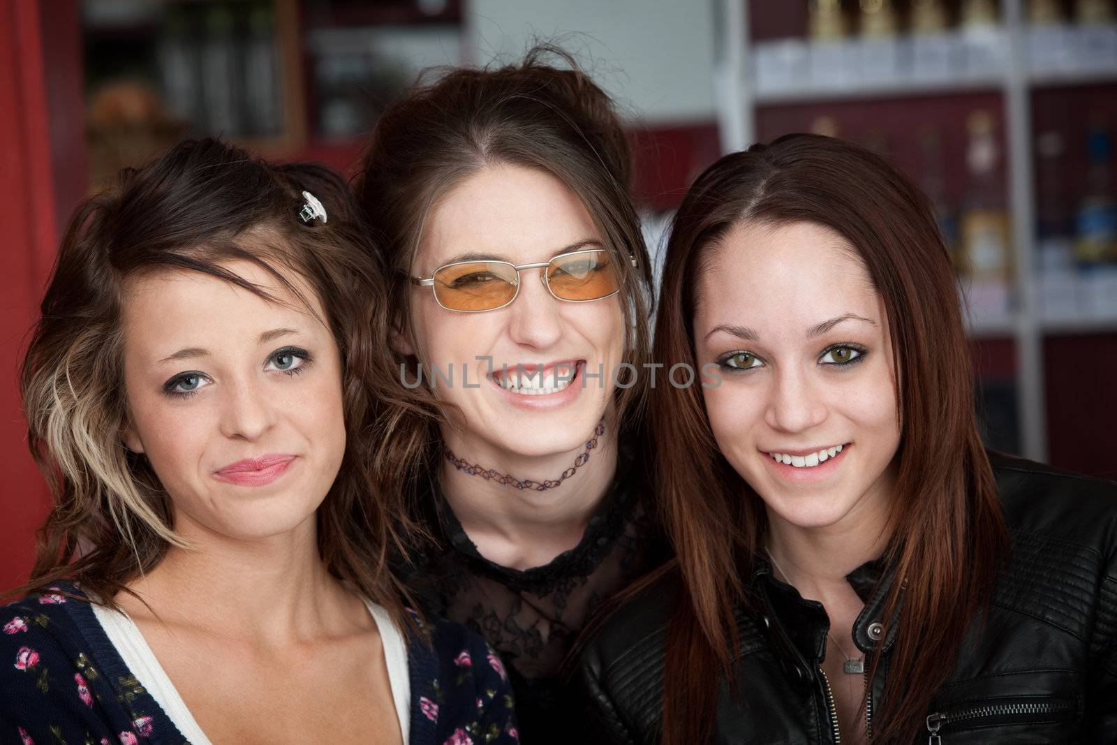 Three young cute teen friends smiling in a cafe