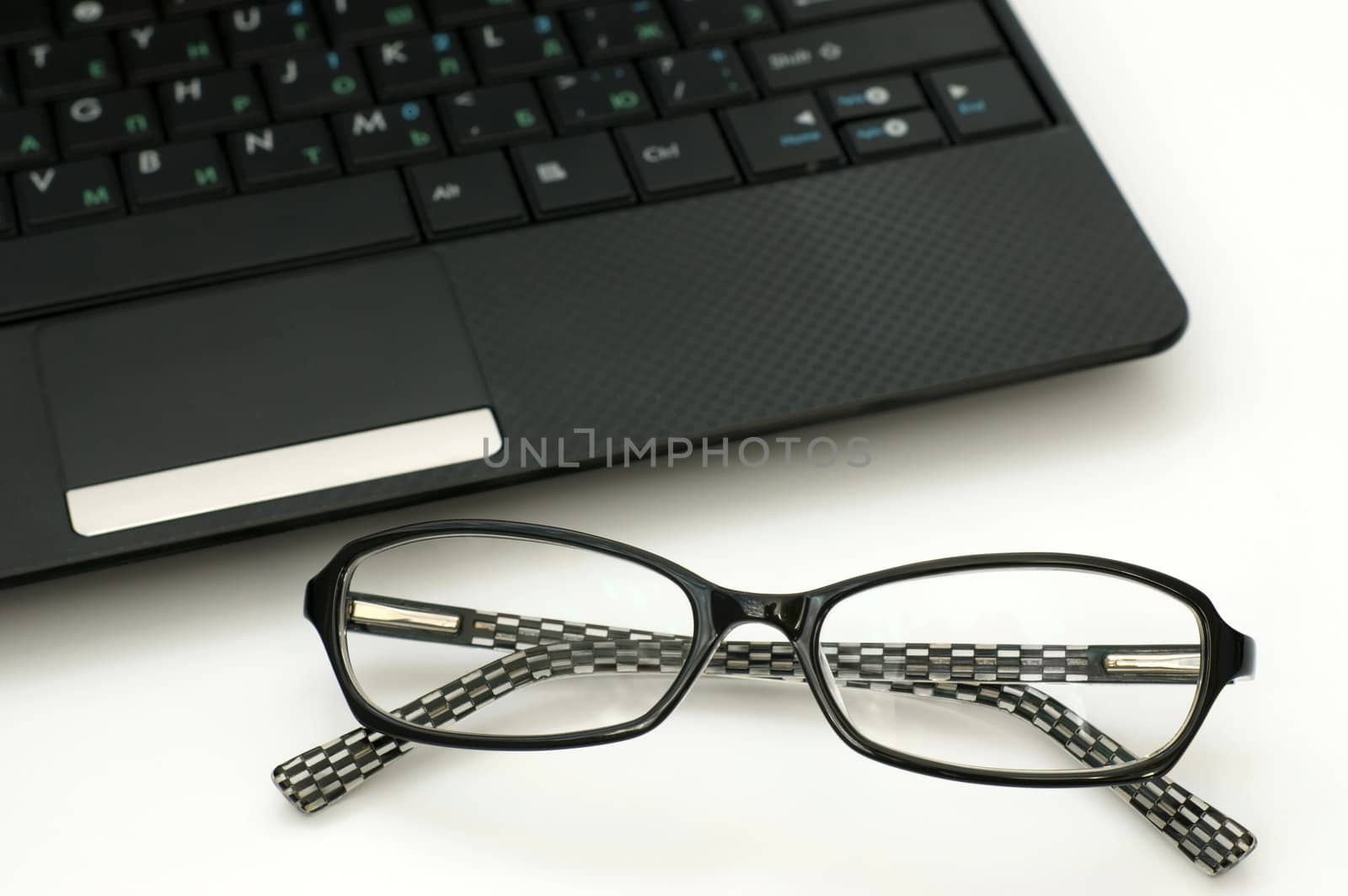 Business glasses near laptop keyboard 