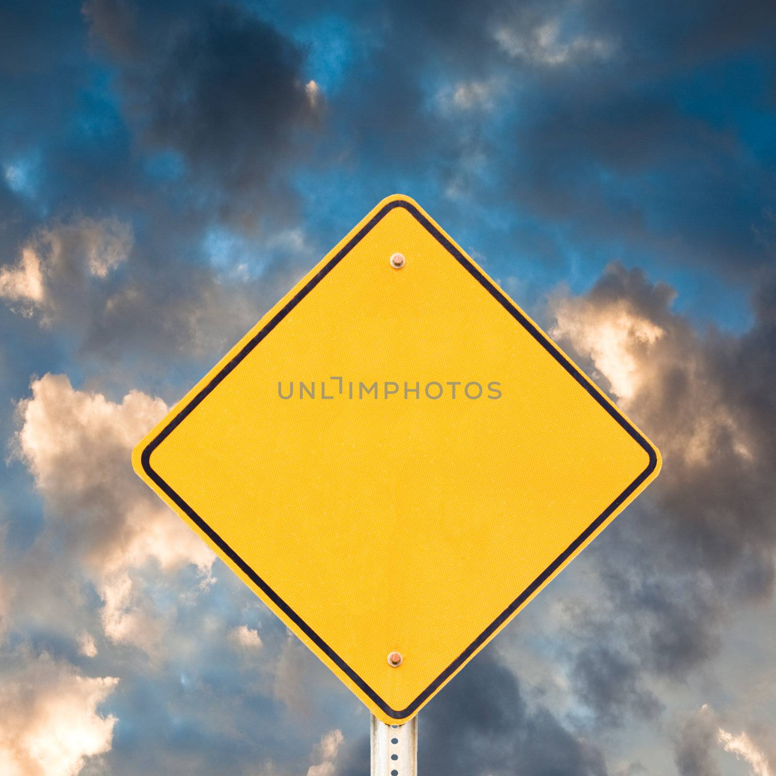 Blank yellow warning road sign with dramatic sky background ready to carry your message.