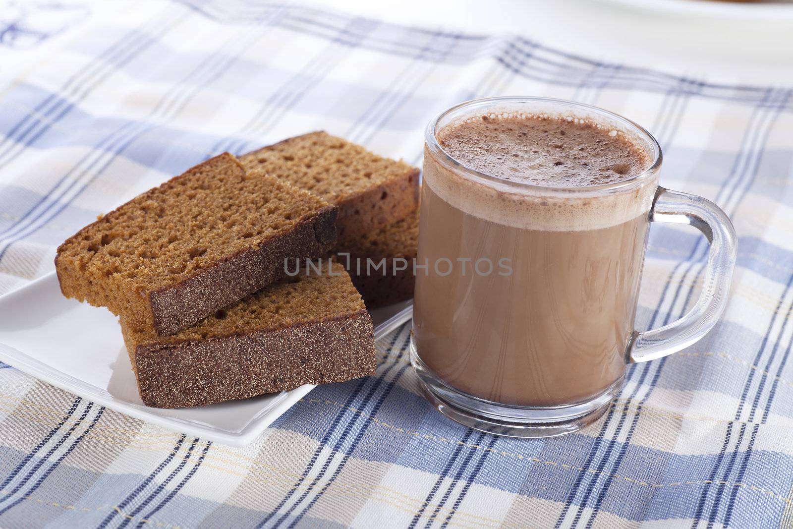 Hot chocolate and sweet spice cake on blue and white cloth.