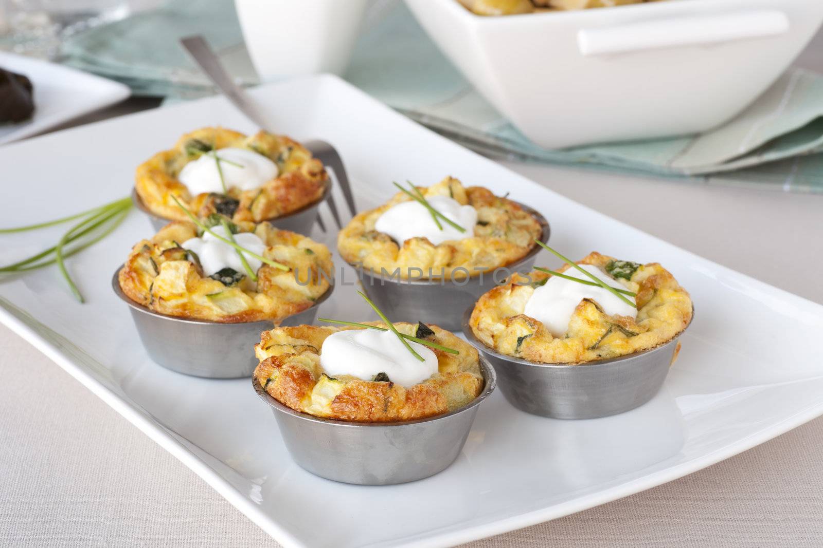 Five quiche appetizers topped with sour cream and chives.