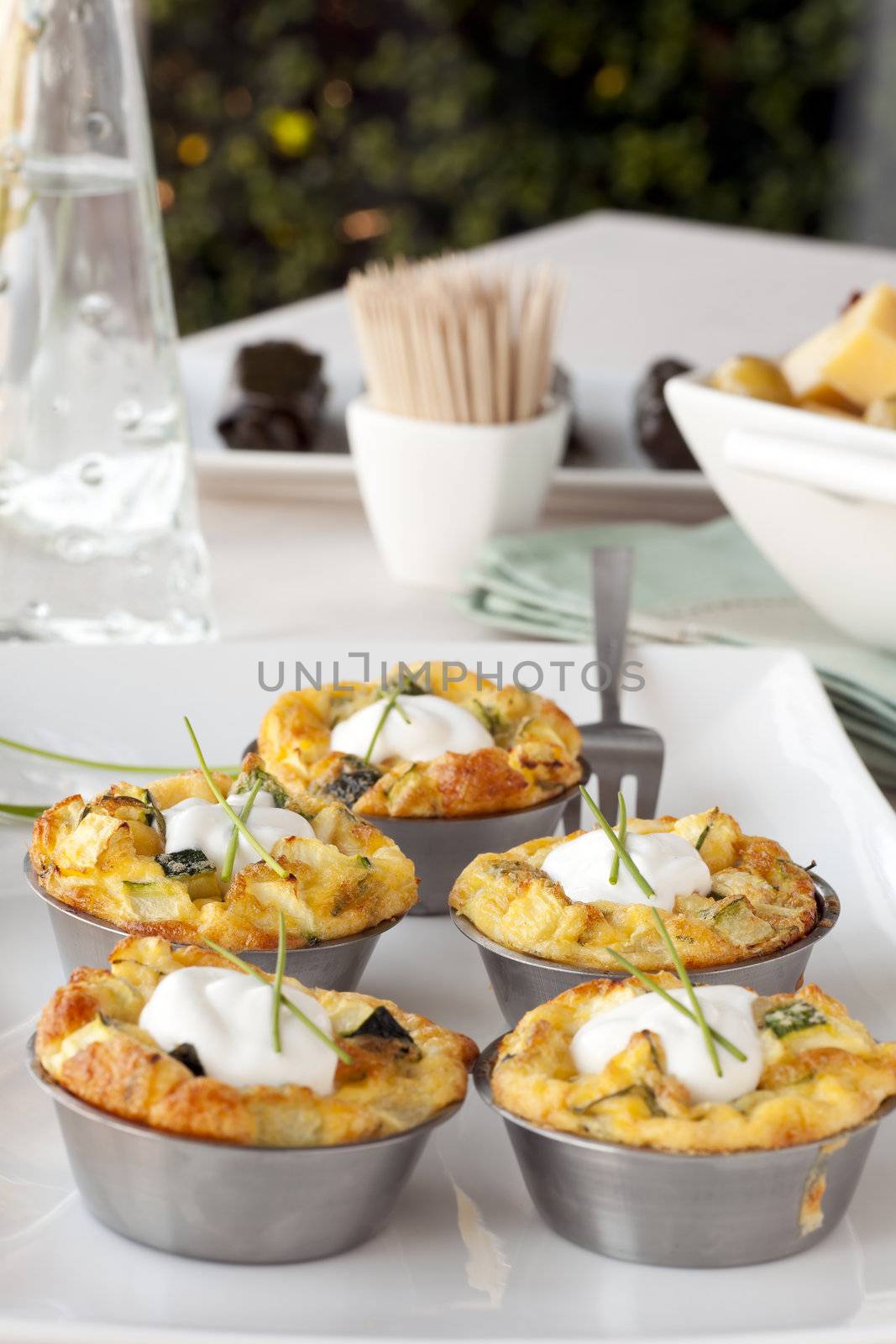 Five quiche appetizers topped with sour cream and chives.