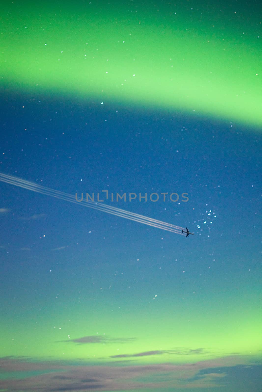 Airplane on moon lit night sky with intense Aurora borealis display and lots of stars.