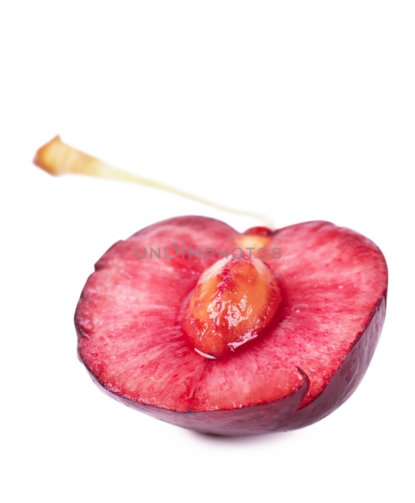Close up view of half of cherry with kernel over white background with shadow