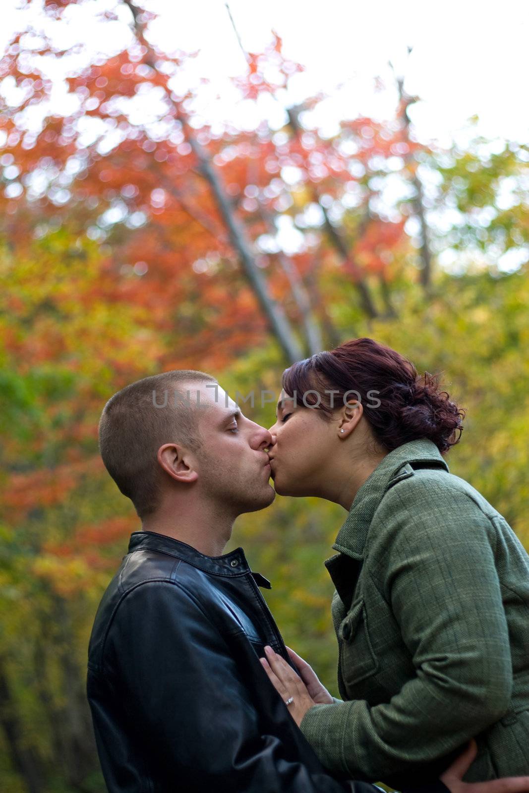 A young happy couple passionately kissing each other outdoors during fall or autumn.