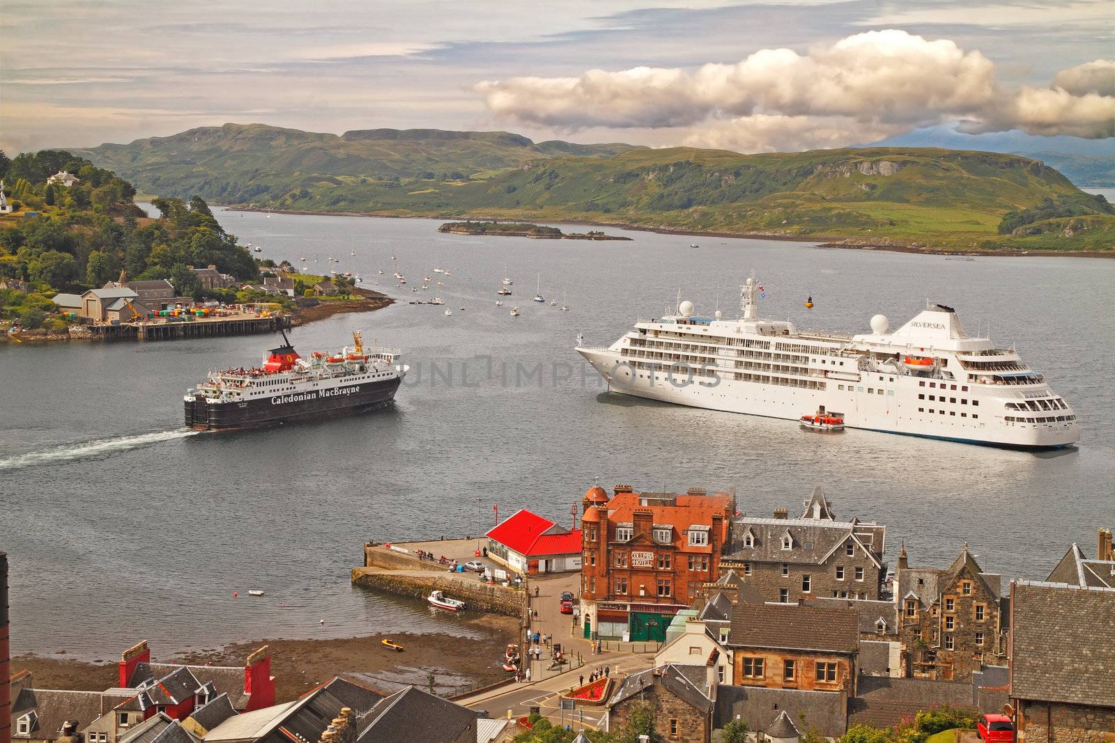 As the ferry leaves for the Western Isles, a cruise ship drops ancher at Oban on the Scottish west coast.