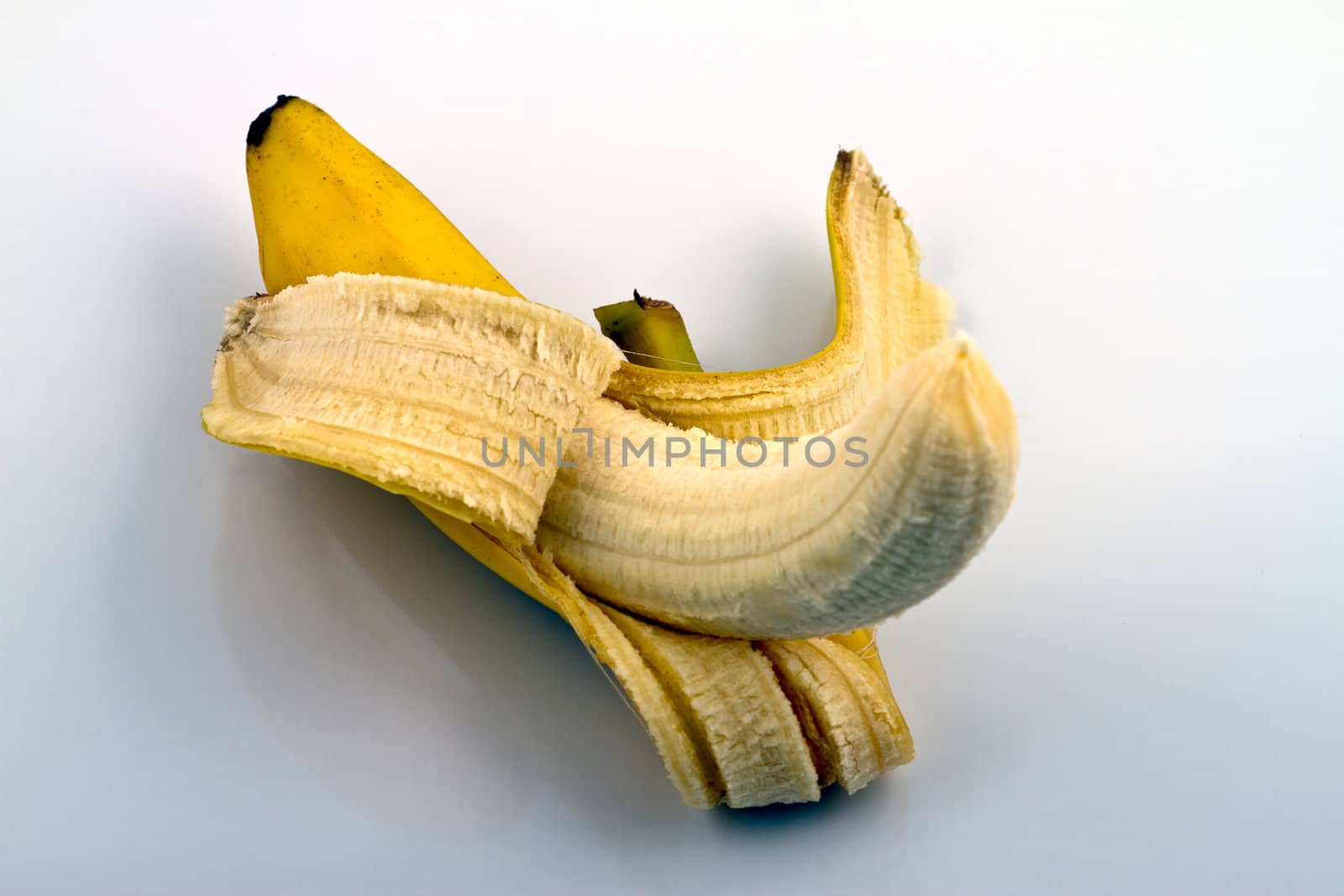 Peeled banana on reflecting white background