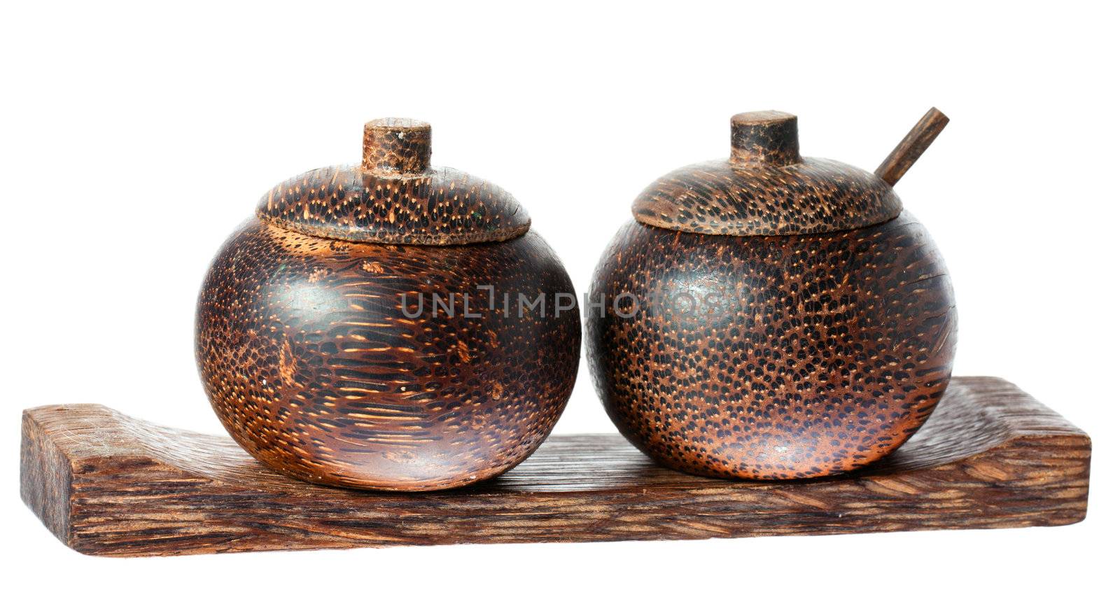 A pair of wooden old fasioned asian style salt and pepper bowls with lids and spoon. Isolated over white with clipping path.
