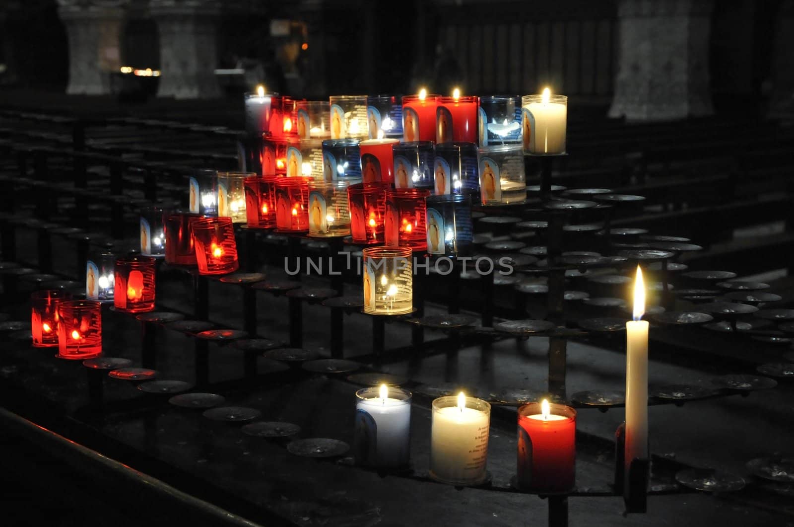 Many religious candles on a black support in a church