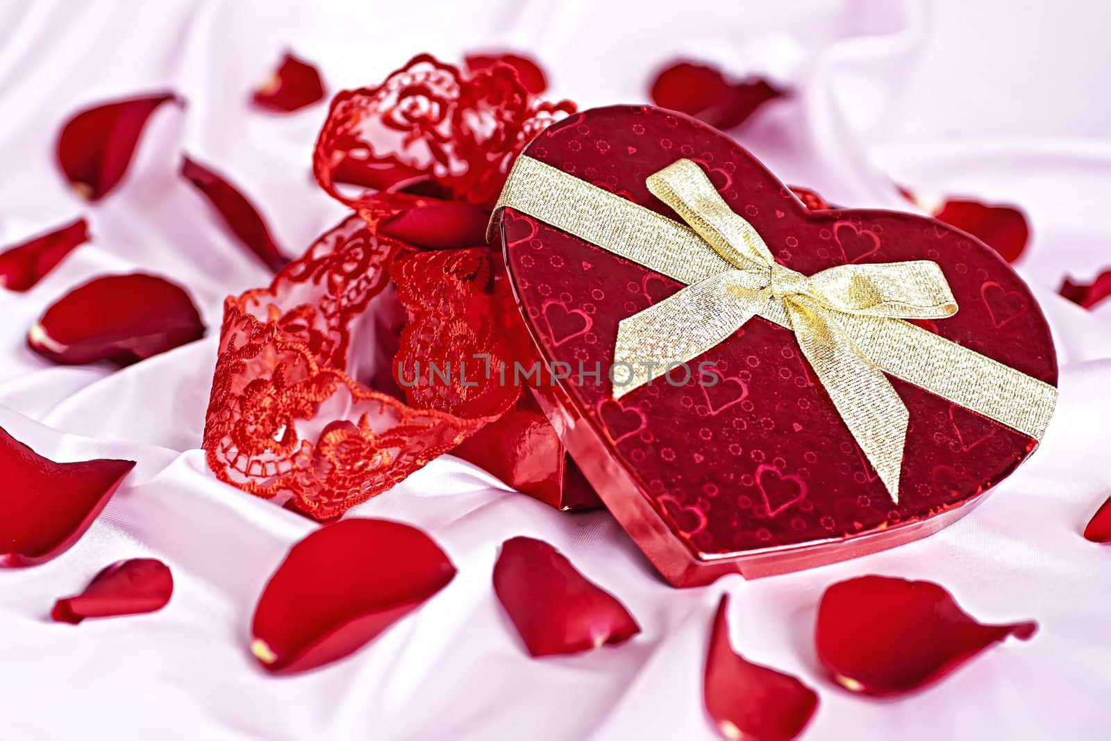 On a pink background gift box heart in the form of women's underwear, the background scattered rose petals.

