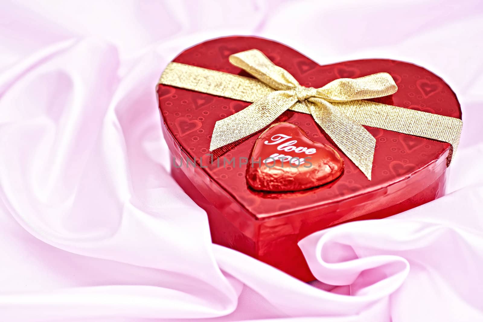 Pink bedding, gift box heart-shaped chocolate candy with the words I Love You. Surprise to the woman.
