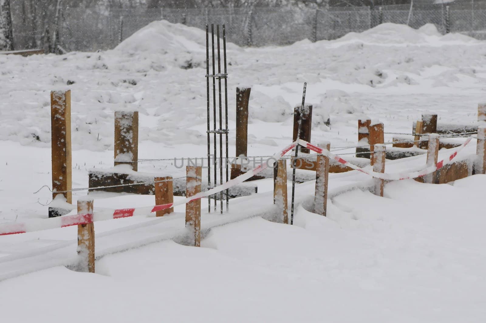 Little construction yard under the snow with wood pickets and iron bars