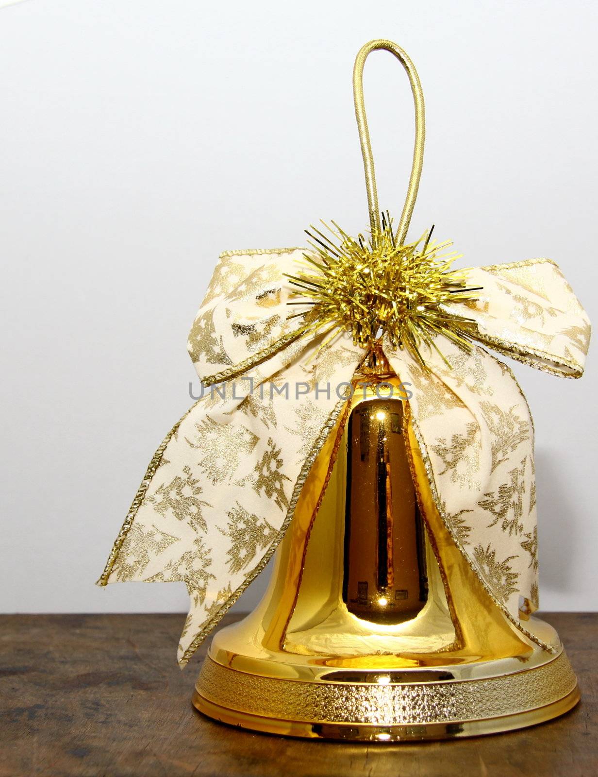 golden christmas bell with a decorative ribbon and gold tinsel