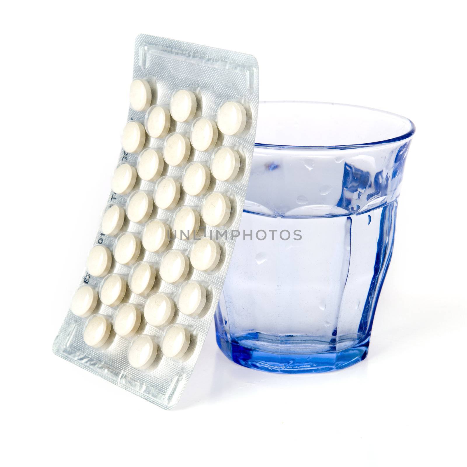 a blue glass and a blister with pills on a white background