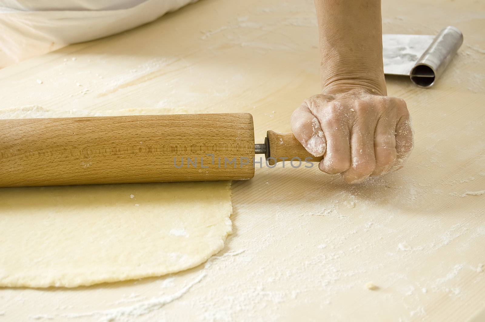 Hand works with rolling pin in kitchen