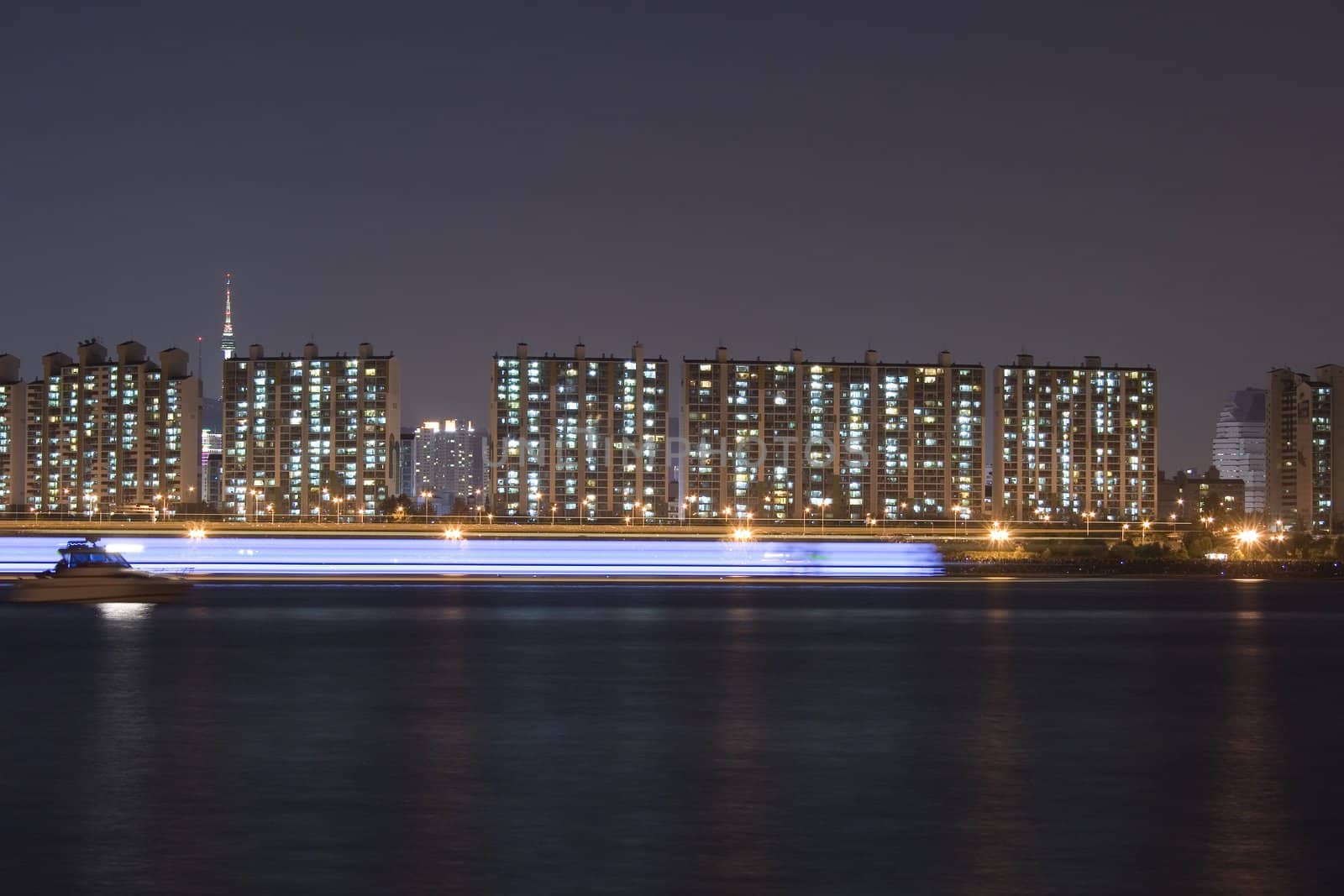 Beautiful lights on apartments relects on the river han in Seoul Korea- with passing ship in motion blur