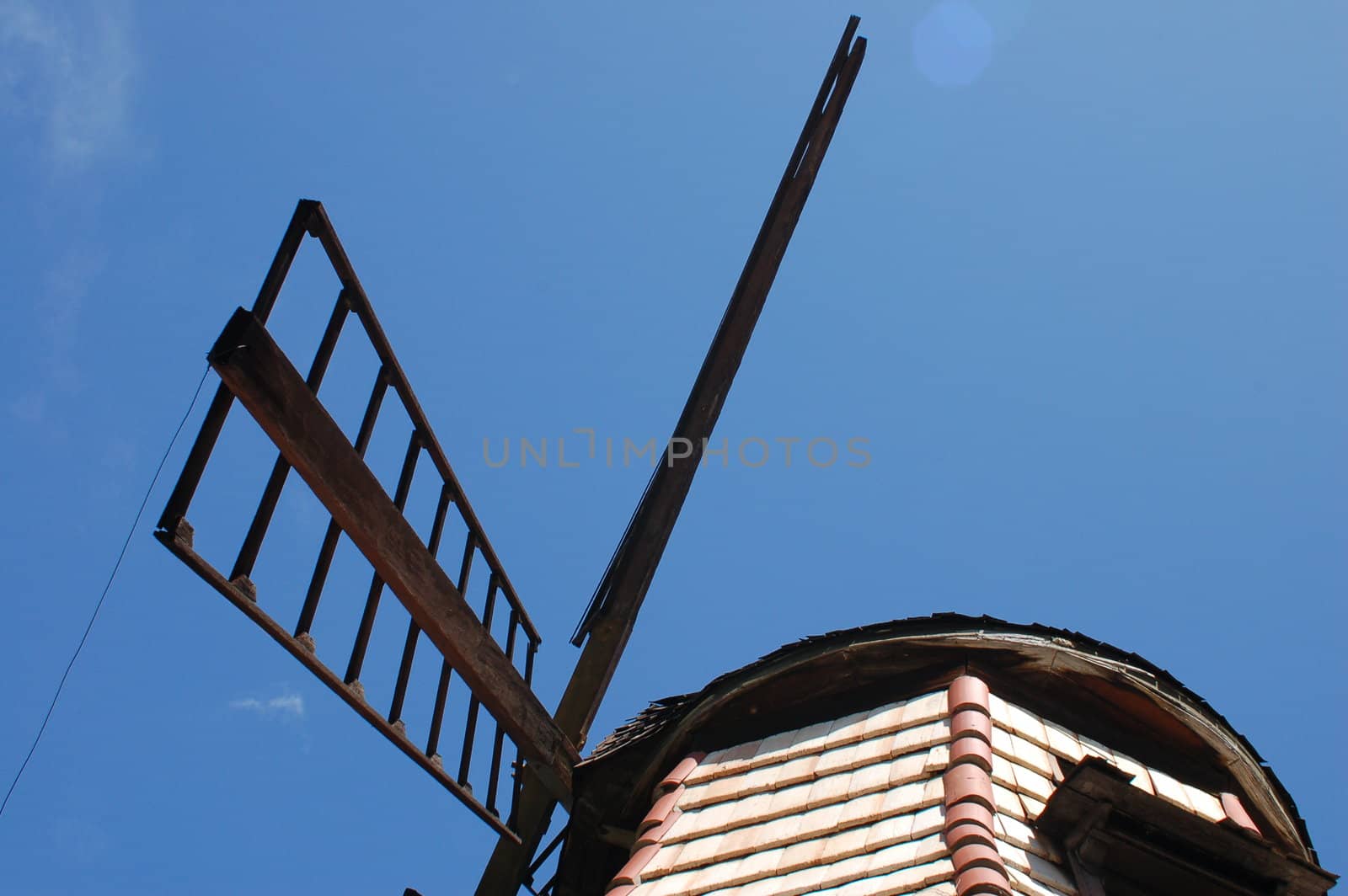Windmill blades and the top of a windmill against a vivid blue sky with copy space.