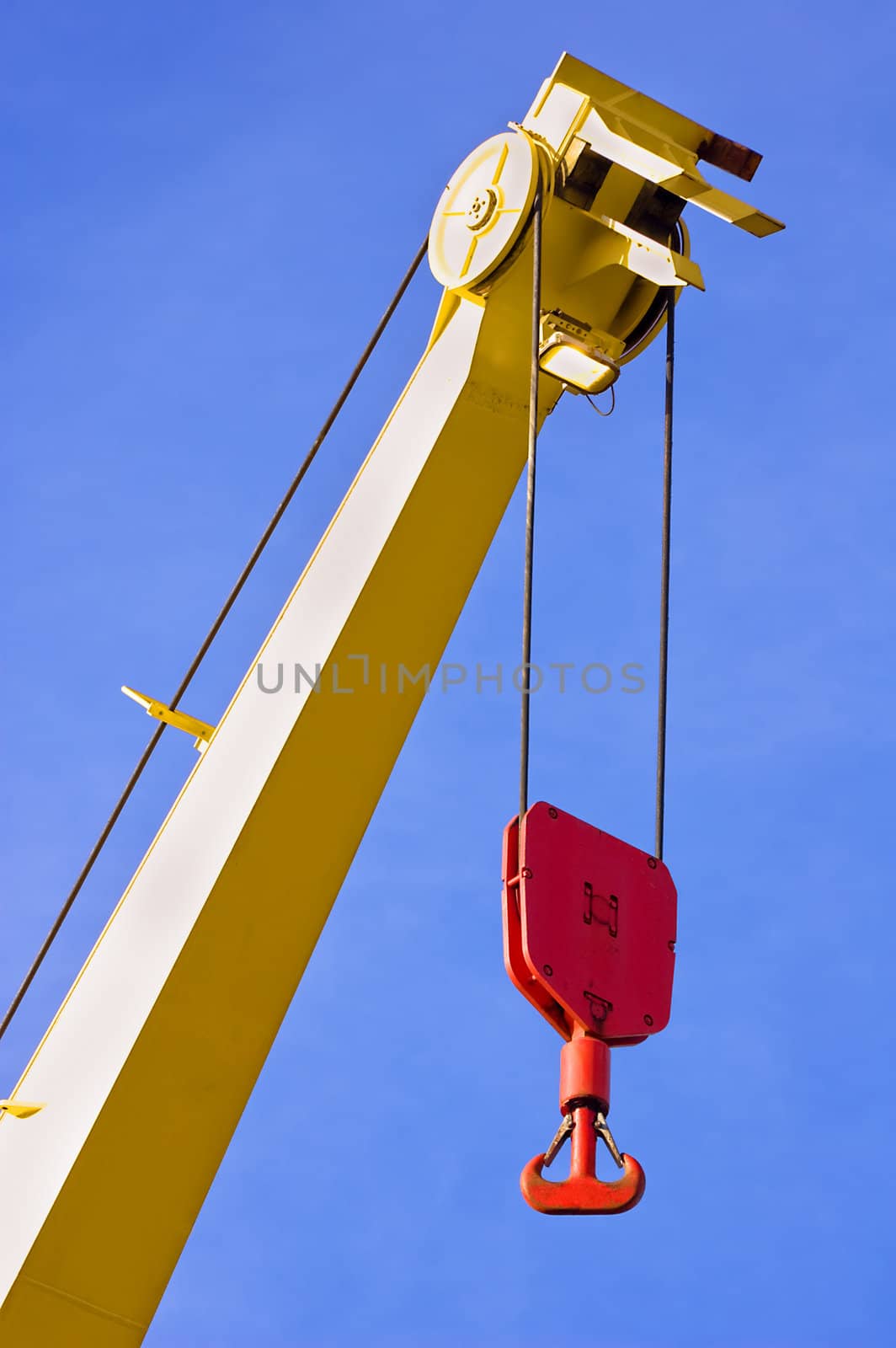 Yellow crane with red hook against blue sky