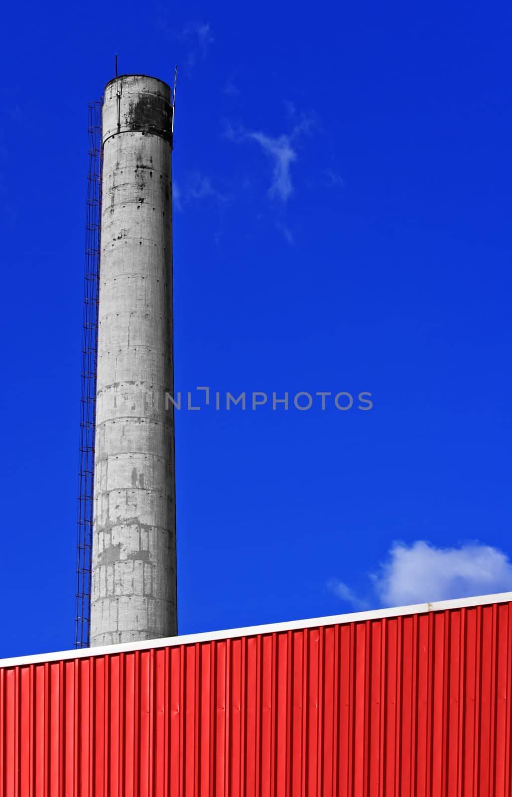 Red factory with a chimney against a blue sky