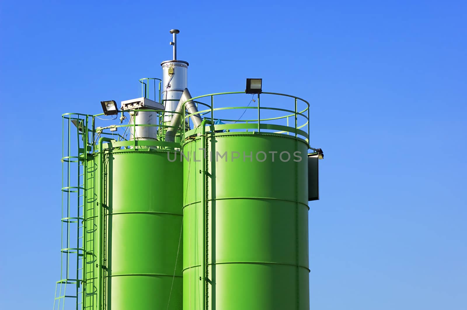 Two green silos agaist blue sky in a construction site