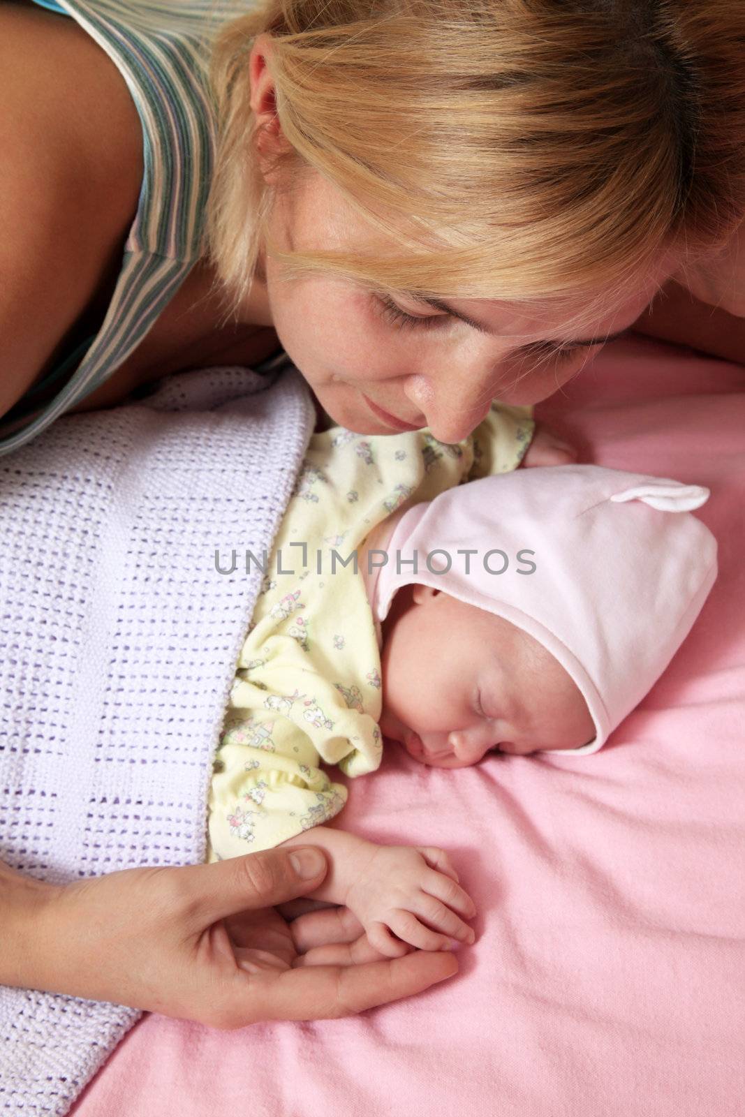 Mother with her sleeping newborn baby in home