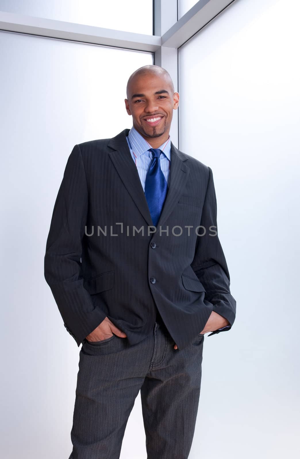 Good-looking smiling businessman standing near office window.