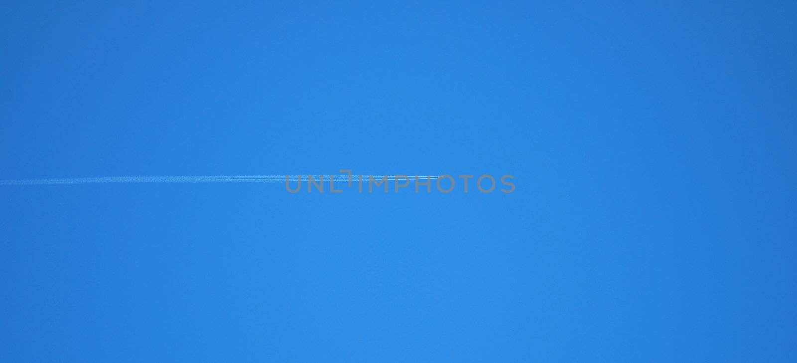 Passenger jet plane on clear, blue sky. Vapor traces parallel to the image edge. 