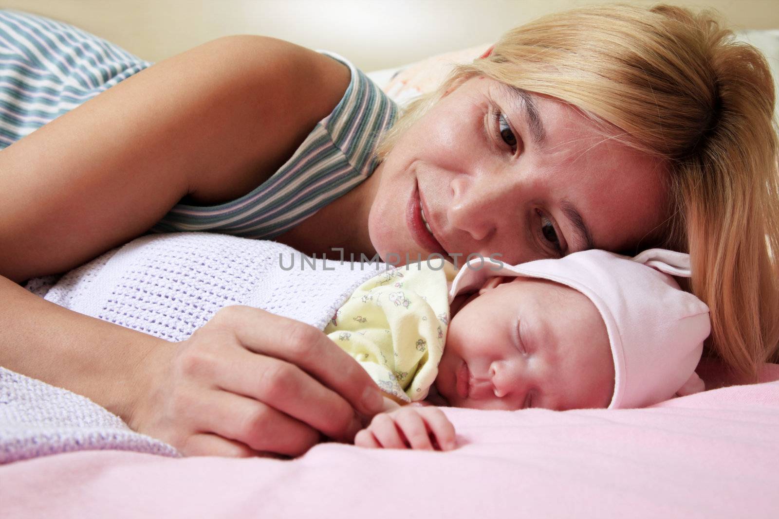 Mother with her sleeping newborn baby in home
