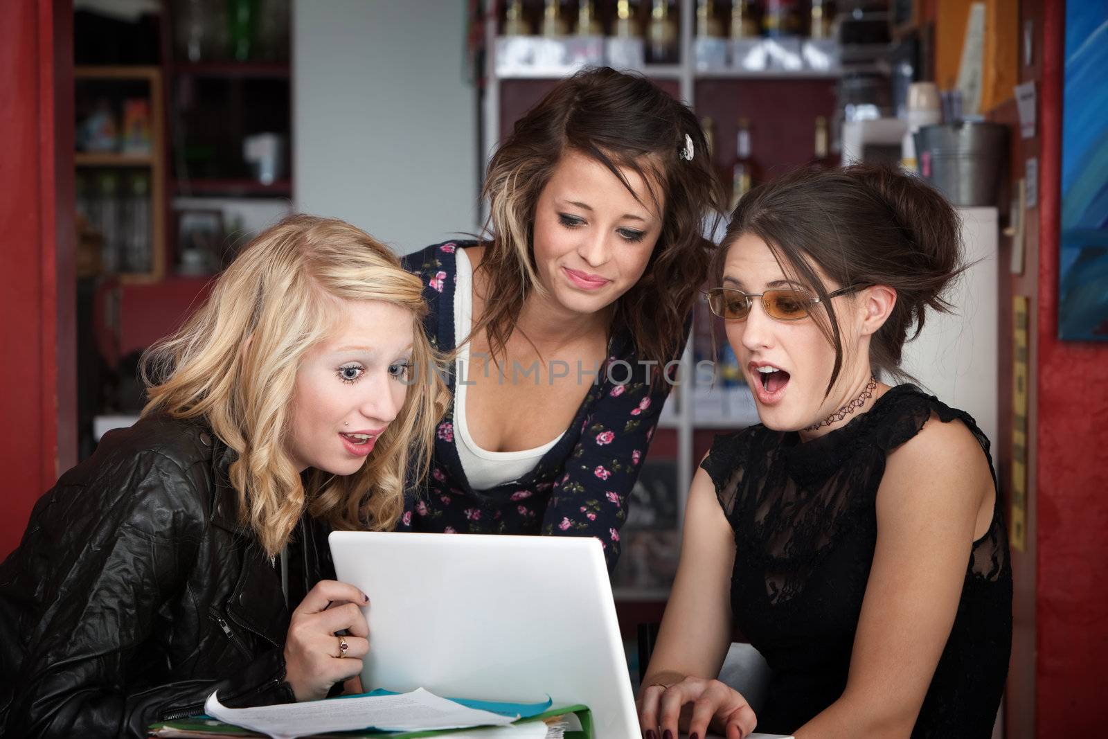 Three young female students surprised while looking at a computer