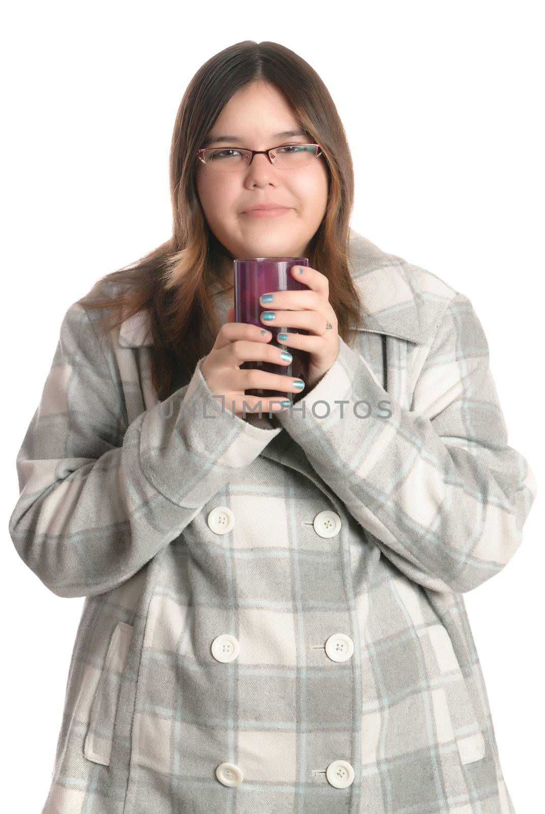 A smiling teenage girl is wearing a fall coat while holding a glass full of juice, isolated against a white background.