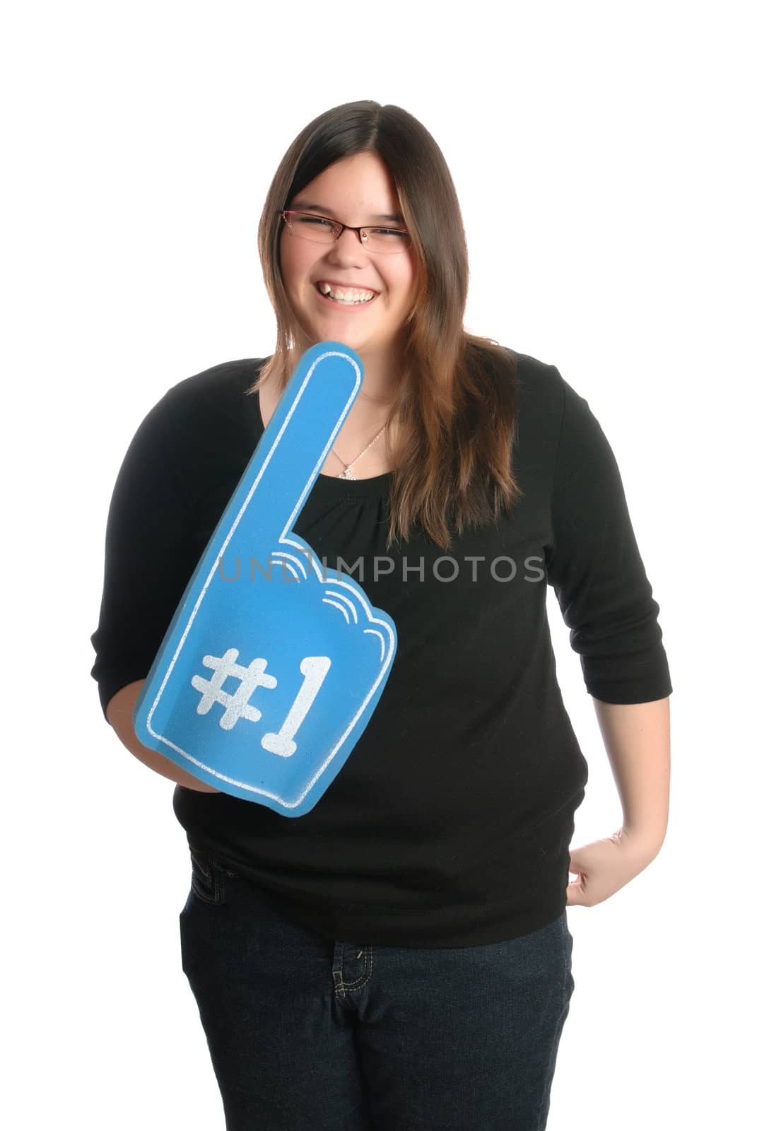 A smiling teenage girl is holding a large foam hand showing that she is number one, isolated against a white background.