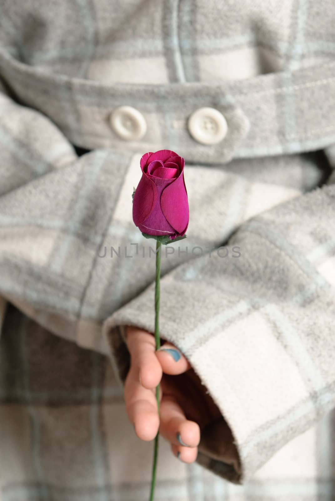 Closeup view of a teenage girl holding a wooden rose behind her back.