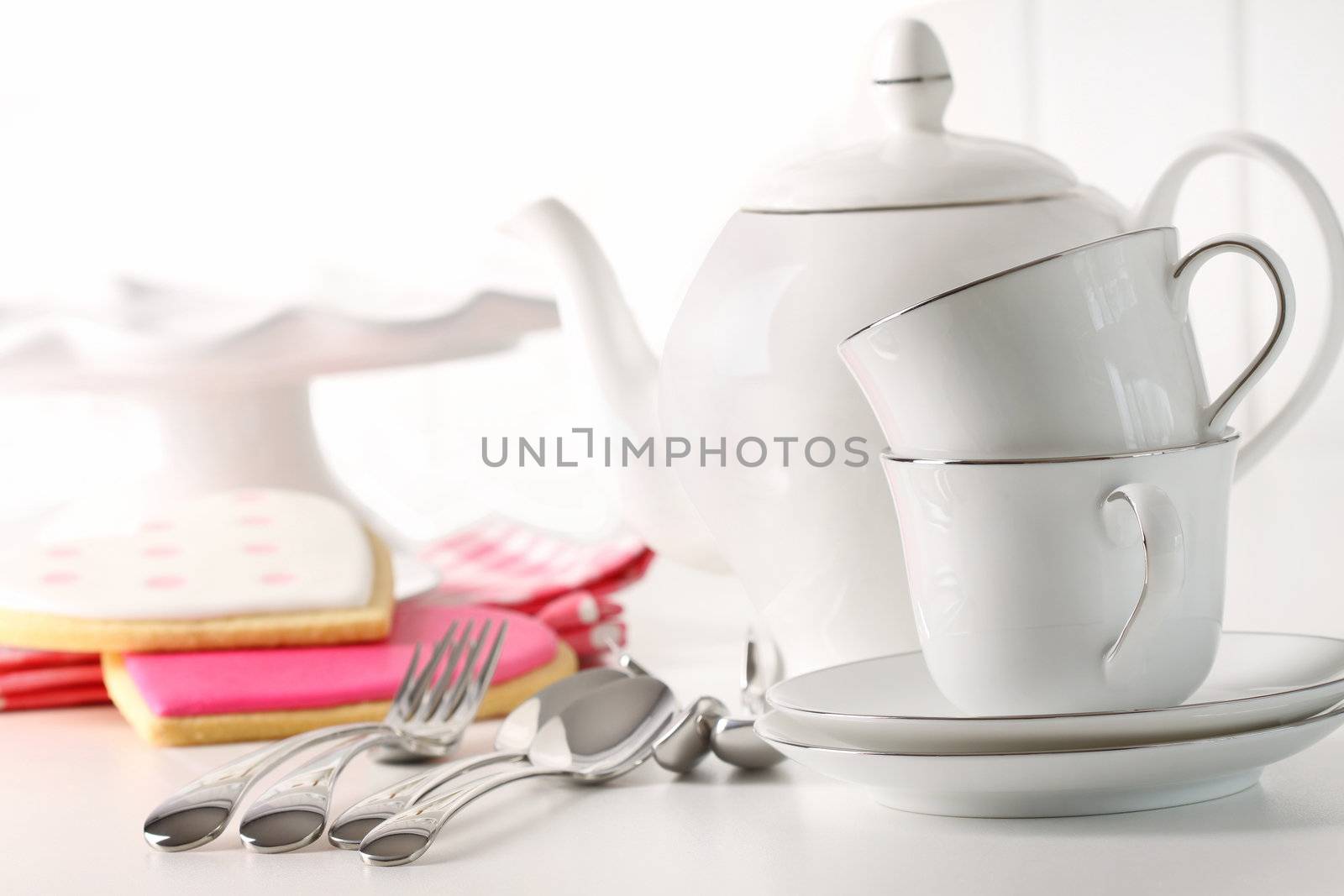 Teapot with cups and valentine cookies in background by Sandralise