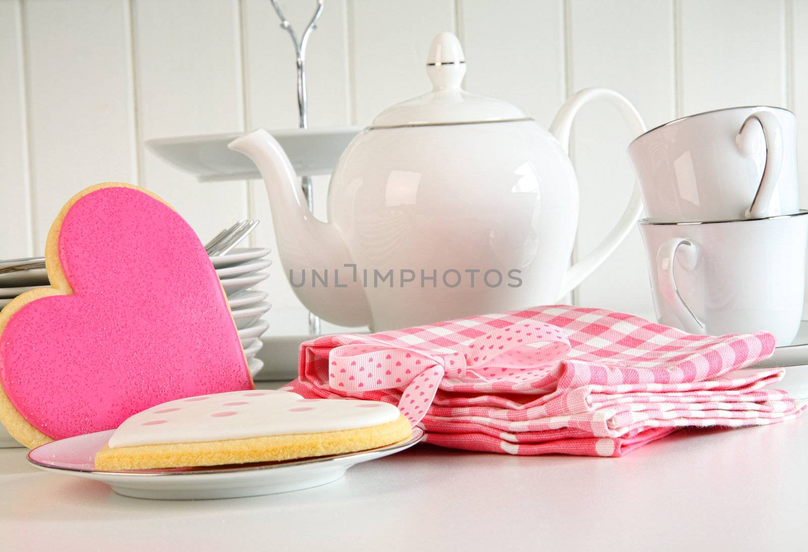 Heart-shape valentine cookies with teapot and cups on kitchen counter
 
