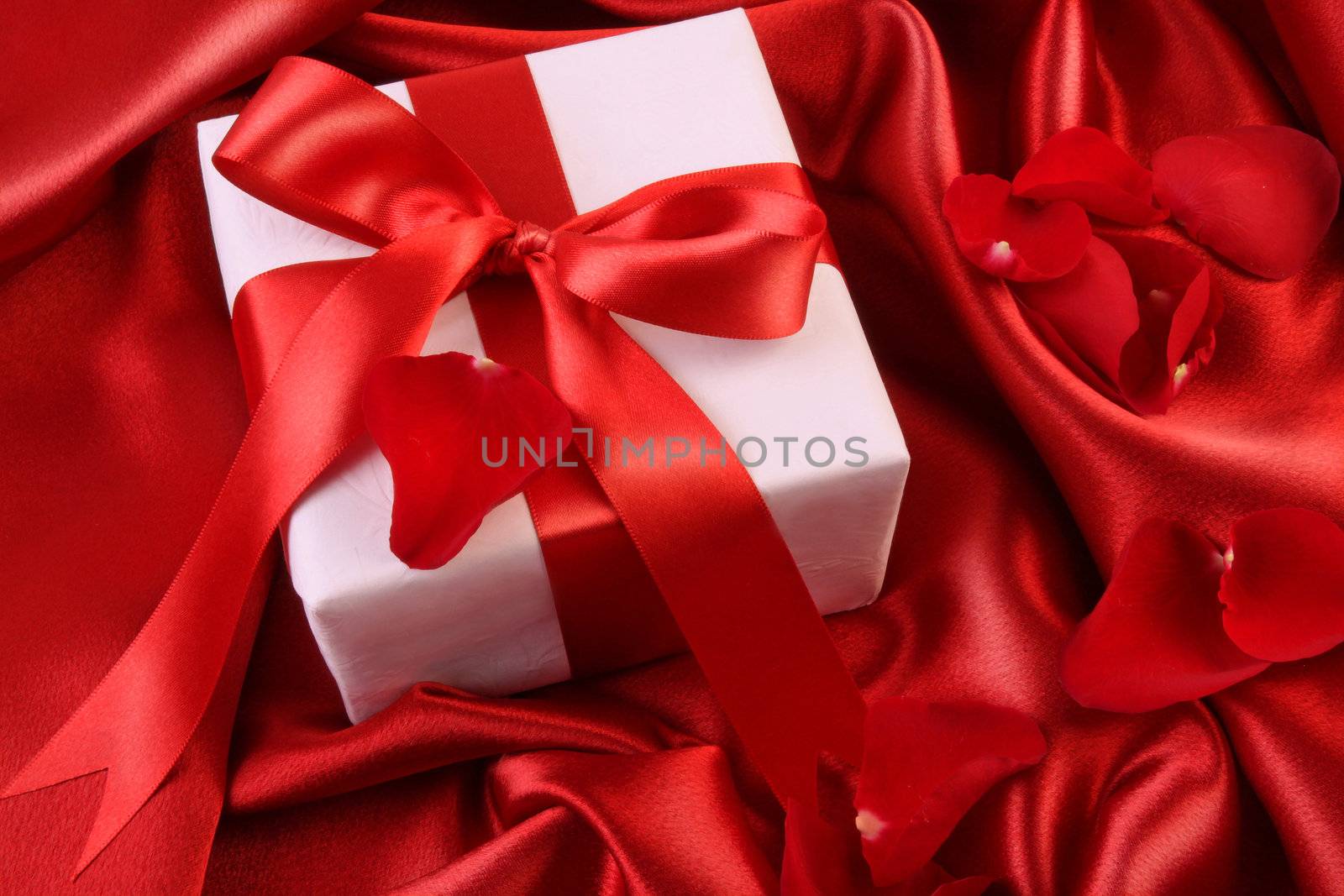 Red ribbon holiday gift on satin silk background