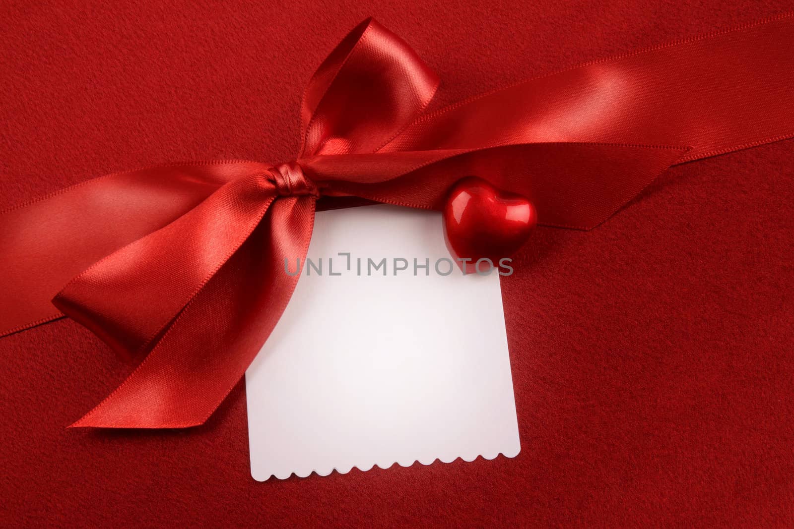 Satin bow and white card for gift on red  by Sandralise