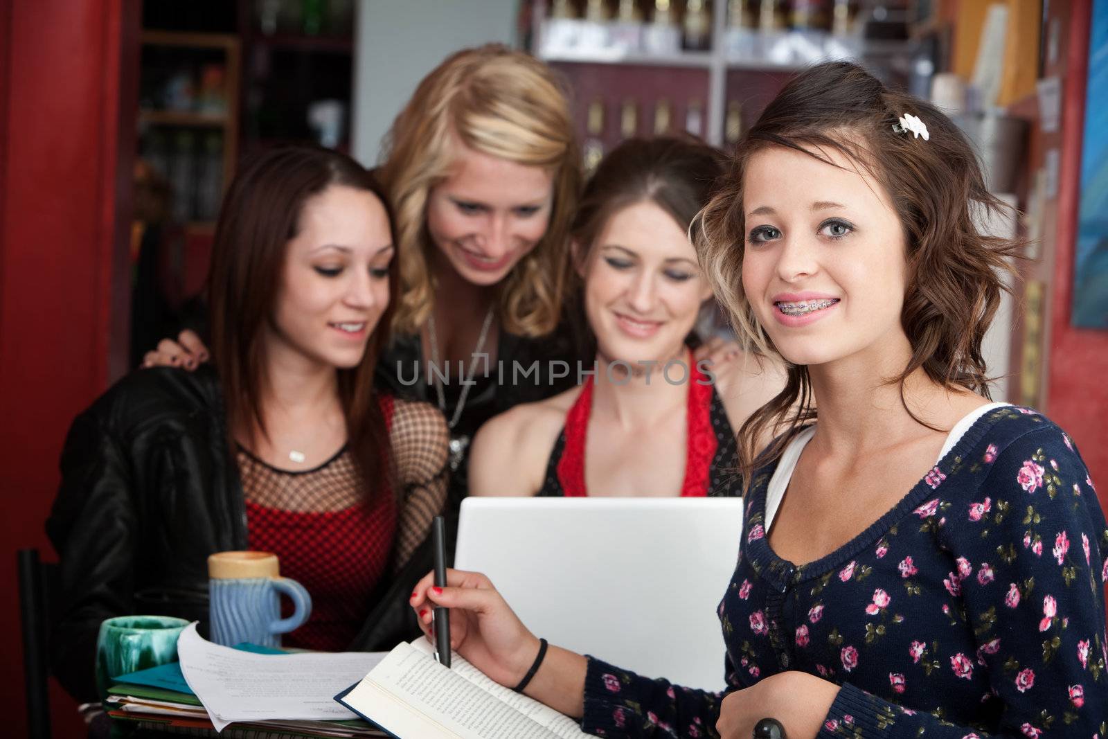 Cute teenaged girl does homework with friends in a cafe