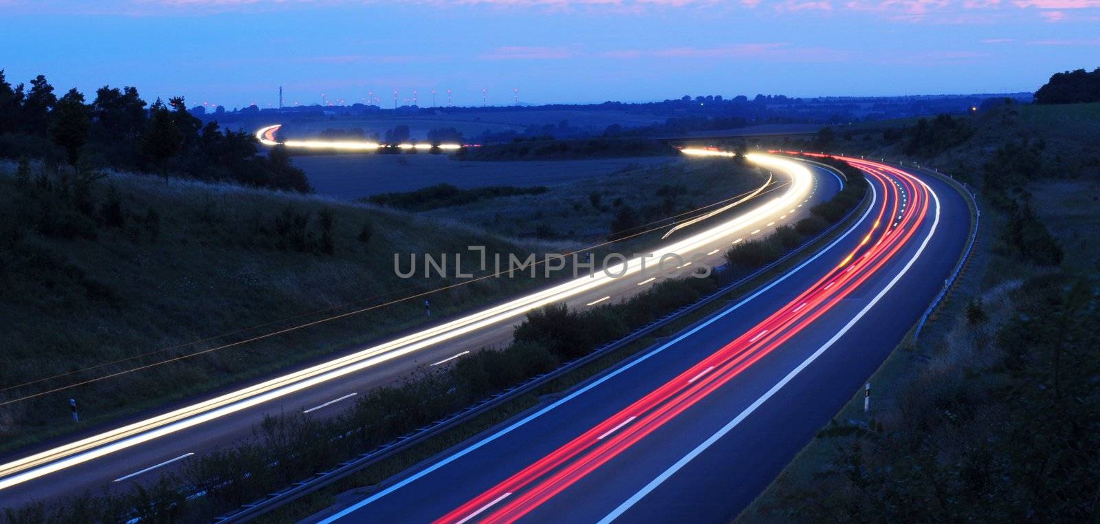 night traffic on busy highway with cars lights and blue sky