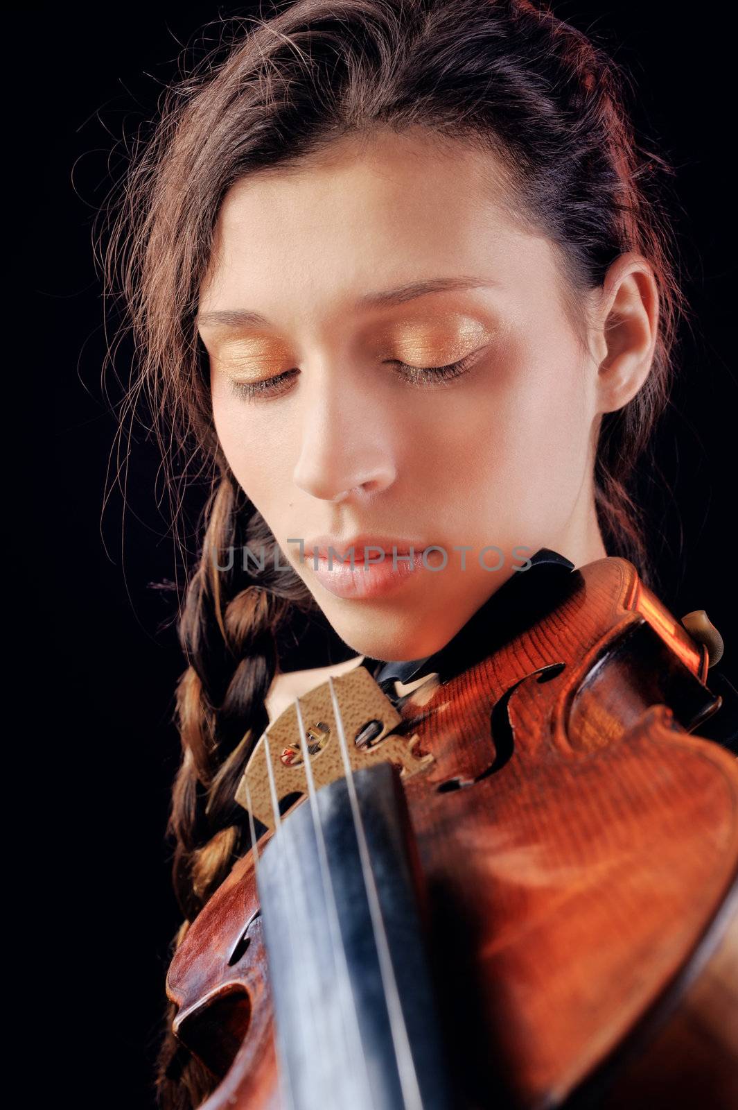 Young woman playing violin. Isolated on the black background