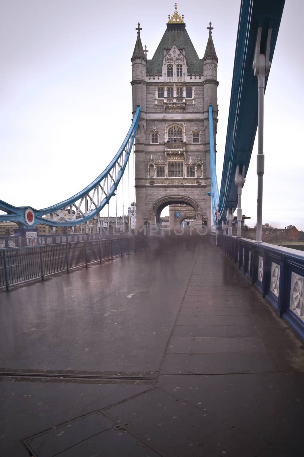 Unusual view of Tower Bridge London against dark moody sky with blurred pedestrians