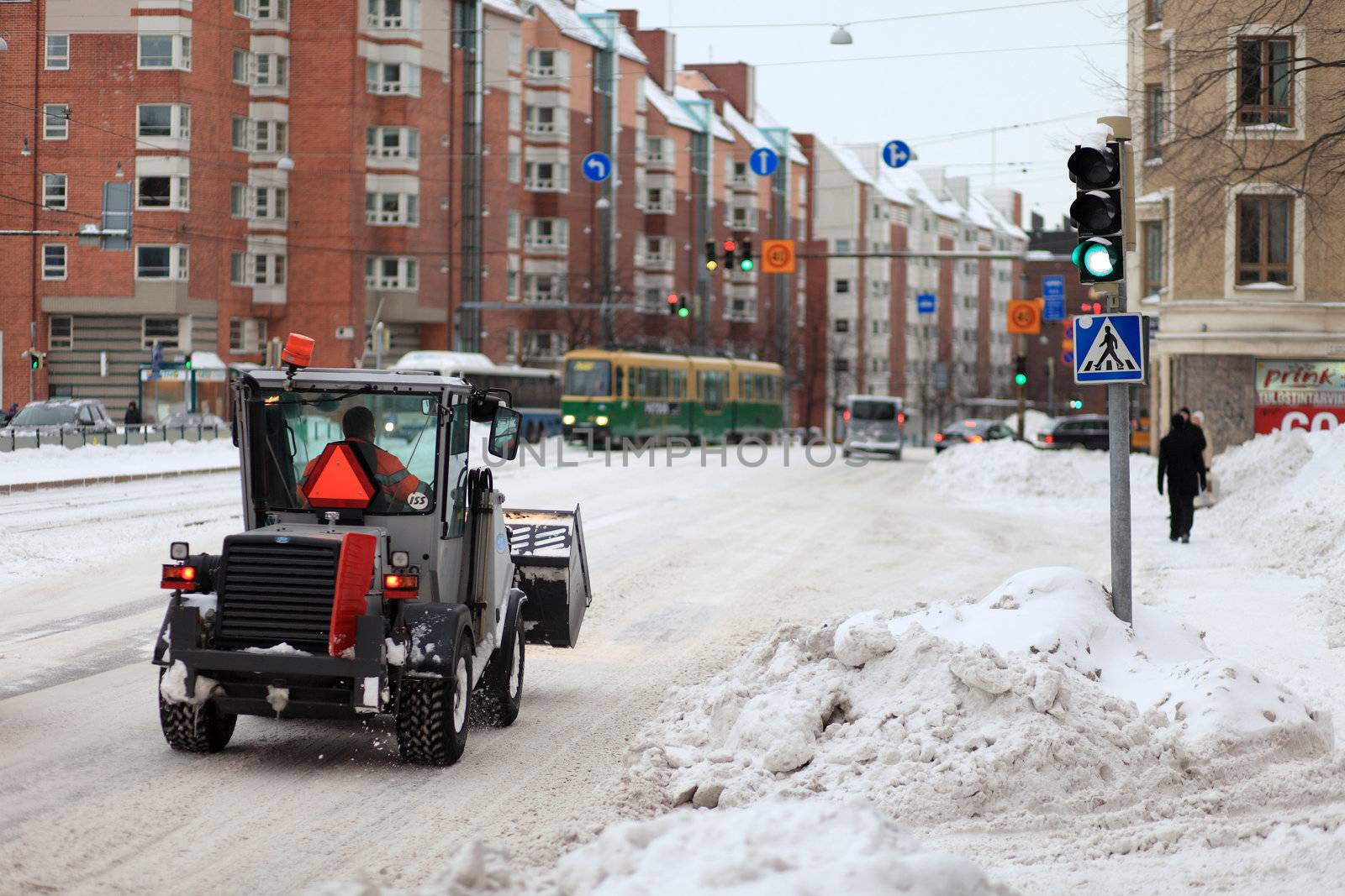 snowy city road with a winter clearance and maintenance service vehicle