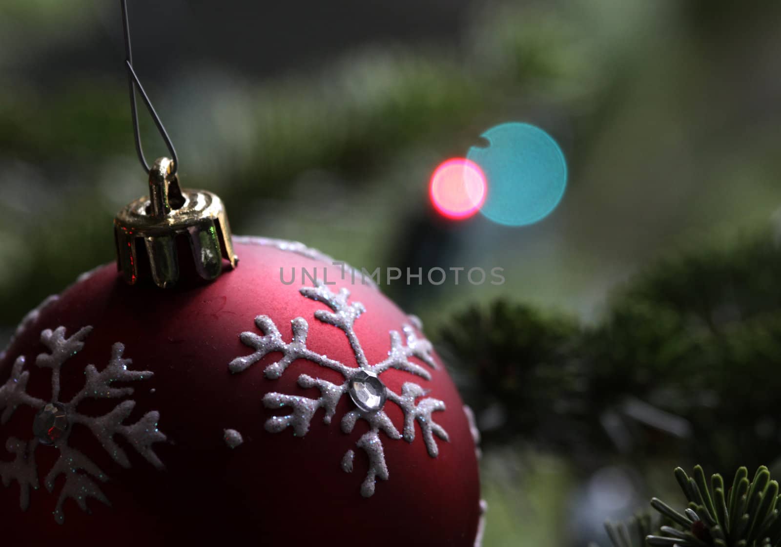 A red snowflake bauble hanging in a Christmas tree.
