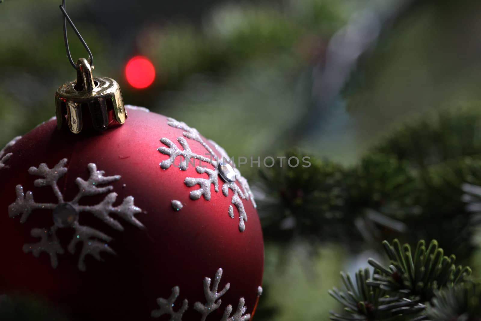 A red snowflake bauble hanging in a Christmas tree.
