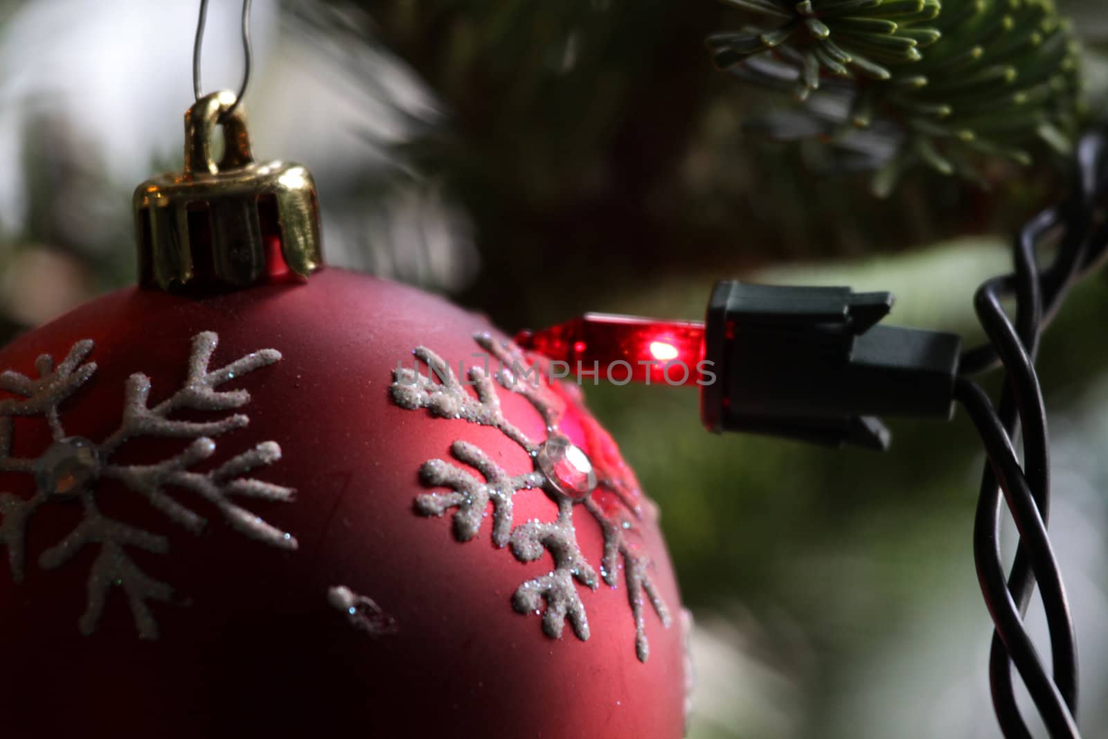 A red snowflake Christmas bauble right next to a red light.