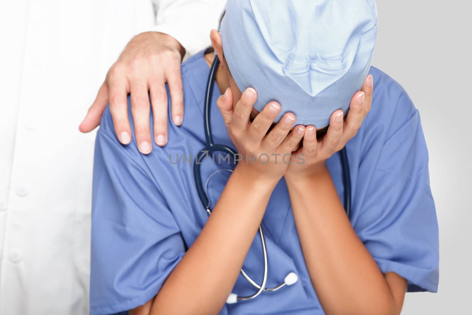 Crying upset nurse / doctor with problems having stress breakdown at work. Colleagues comforting her.