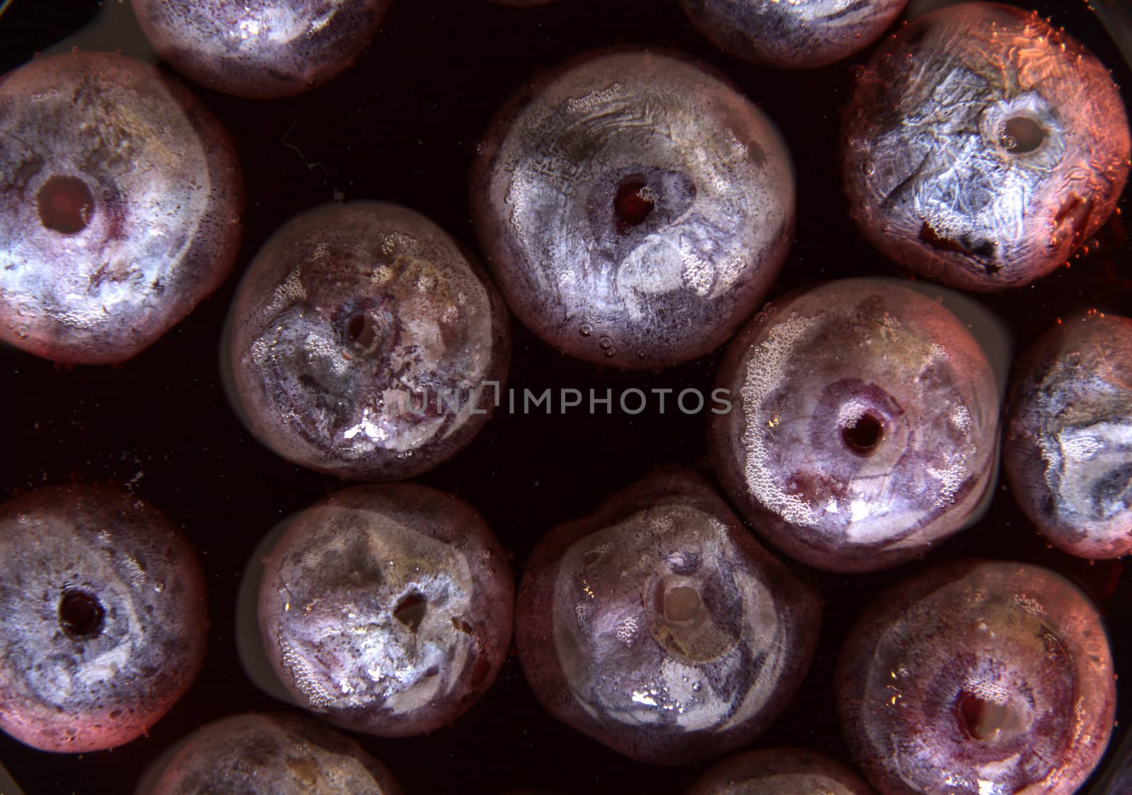 A shot of grape juice with grapes floating in it.
