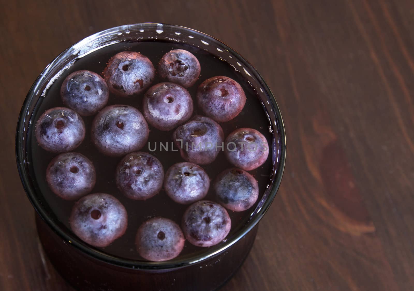 A shot of grape juice with grapes floating in it.
