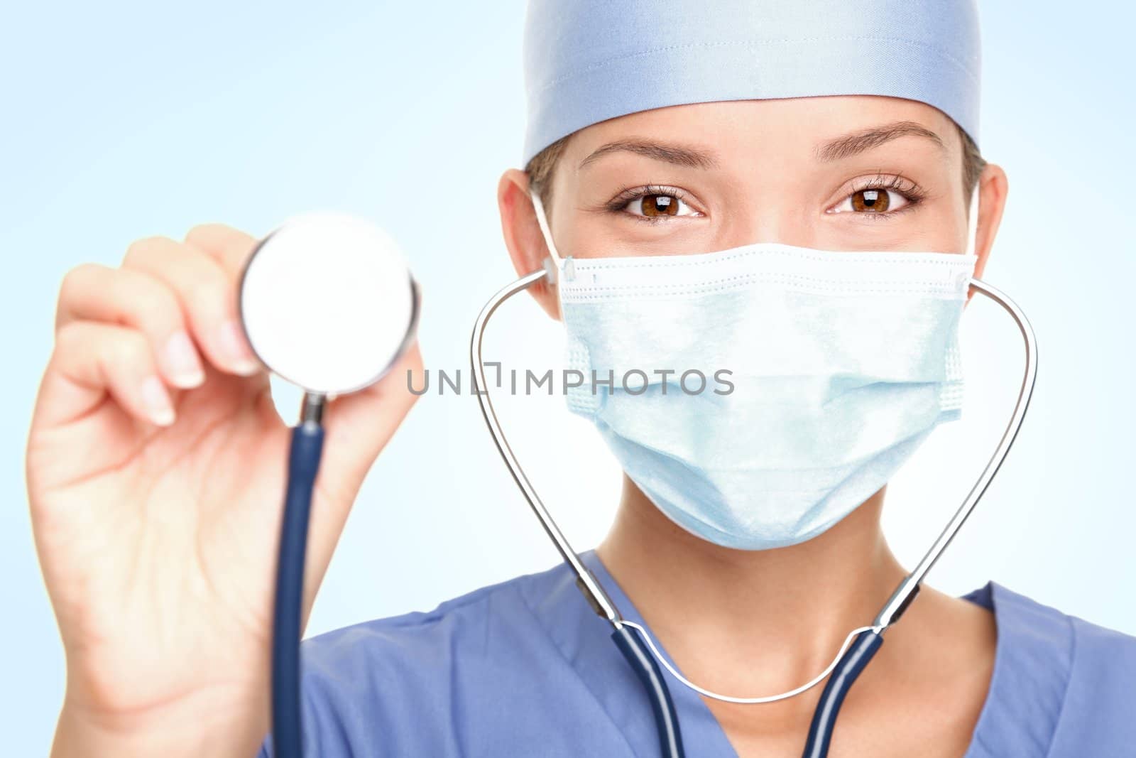 Young doctor / surgeon showing stethoscope wearing surgeon mask looking at camera. Asian / Caucasian female model. 