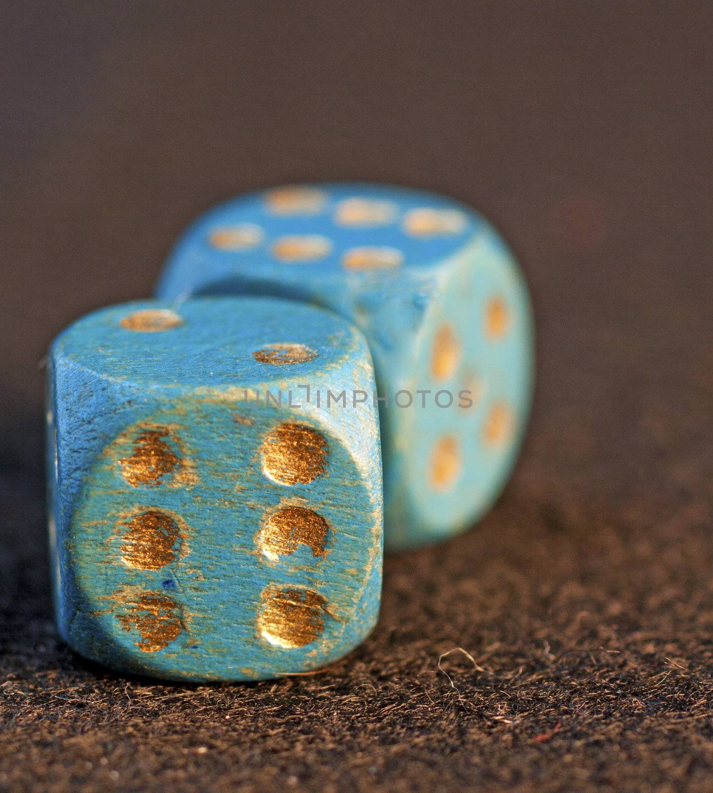 Old blue dice with golden numbers over black background