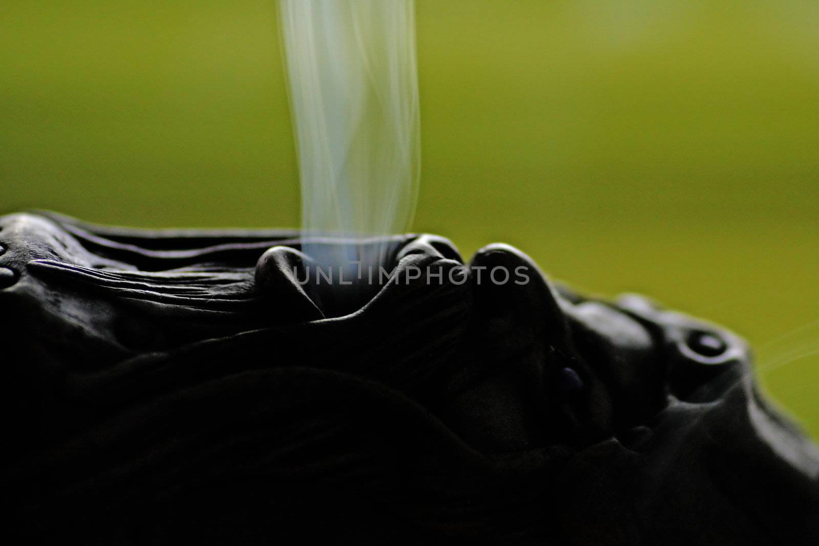 Close view of a smoking doll with smoke getting out of it's mouth.